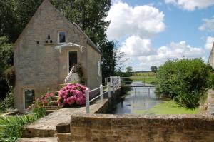 an old stone church with a bridge over a pond at Cottage d'Exception - Coeur de Normandie 