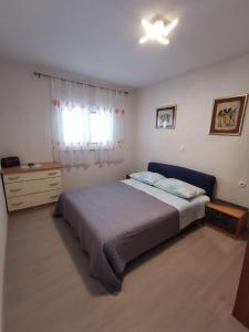 ein Schlafzimmer mit einem Bett, einer Kommode und einem Fenster in der Unterkunft Apartment Nera in Omiš