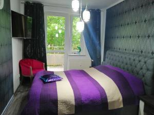a purple and white bed in a room with a window at Apartament Nadmorski in Kołobrzeg