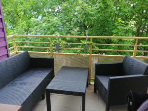 two blue chairs and tables on a balcony with trees at Apartament Nadmorski in Kołobrzeg