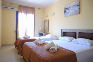 due letti in una camera d'albergo con asciugamani sopra di Edelweiss Studios a Limenas