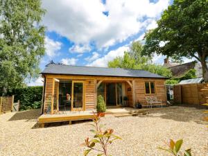 a small wooden cabin with a patio in a yard at Goose Lodge in Shipston on Stour