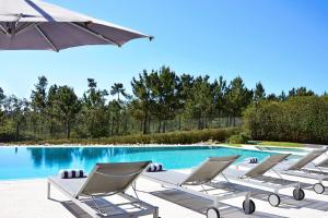 - un groupe de chaises longues à côté de la piscine dans l'établissement Villa Morena, à Charneca