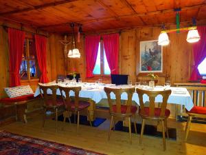 ein Esszimmer mit einem Tisch mit Stühlen und roten Vorhängen in der Unterkunft Gasthof Auerhahn in Lech am Arlberg