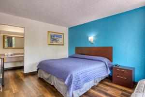a bedroom with a bed with a blue wall at Zen Living Suites Extended Stay - Jacksonville - Orange Park in Orange Park