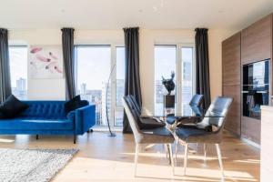 a living room with a blue couch and a glass table at Luxury river side penthouse in London