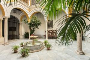 a courtyard with a fountain and plants in a building at Mágico apartamento en casa palacio del siglo XVII in Seville