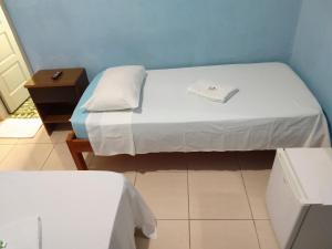 a small room with a bed with a book on it at Hotel Paulista in São Vicente