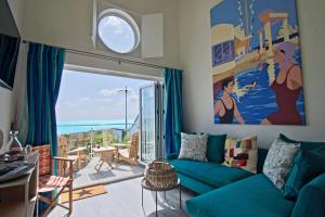 a living room with a blue couch and a large window at Beach Hut Suites in Bognor Regis