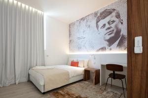 a white bedroom with a bed and a chair at The ICONS Lisbon Central Hotel in Lisbon