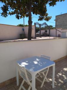 a white table and a chair next to a tree at Magnolia Rooms in Civitavecchia