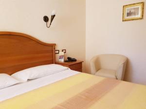 una camera con letto, sedia e lampada di Hotel Ristorante L'Avvenire a Gizzeria