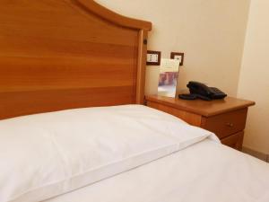 un letto con testiera in legno e telefono di Hotel Ristorante L'Avvenire a Gizzeria