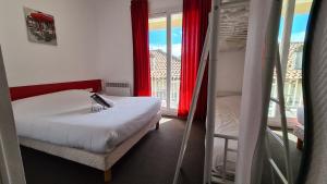 een slaapkamer met een bed en een raam met uitzicht bij Hotel Les Vieux Acacias in Queyrac