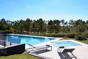 a swimming pool with two lawn chairs and a swimming pool at Villa Morena in Charneca