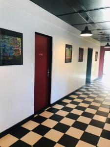 um corredor com uma porta vermelha e um piso xadrez em Hebergements le Camp d'Auneau - Le Clos du Camp em Auneau