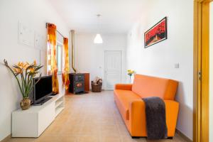 een woonkamer met een oranje bank en een tv bij ARADAS, Pampilhosa da Serra, Casa da Oliveira, Wifi, Ar Condicionado, Churrasqueira, Parqueamento, by IG in Unhais-o-Velho