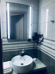 ein Badezimmer mit einem weißen Waschbecken und einem Spiegel in der Unterkunft Angela Apartments & Studio in Fanárion