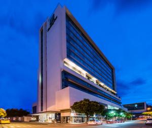 wysoki biały budynek z samochodami zaparkowanymi przed nim w obiekcie Holiday Inn Cúcuta, an IHG Hotel w mieście Cúcuta