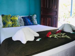 Una cama con dos toallas y flores. en All Rankins Eco-Lodge, en Tortuguero