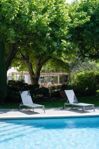 dos sillas blancas sentadas junto a una piscina en Hôtel Montmirail, en Gigondas