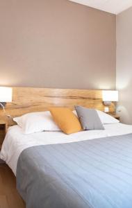 a bedroom with a large bed with two lamps on it at Hôtel Montmirail in Gigondas