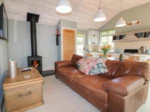 a living room with a brown leather couch and a stove at The Hen House in Rugeley