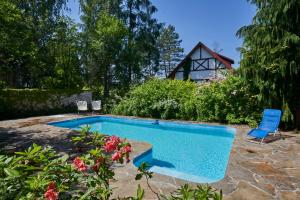 a swimming pool in a yard with two chairs and flowers at Pod Lasem in Ludwinów