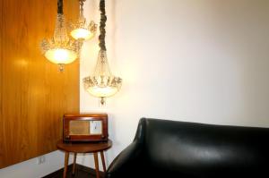 a room with a chair and a tv and chandeliers at Moderna in Coimbra