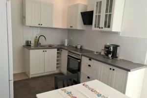 a kitchen with white cabinets and a black stove top oven at Apartament Barbara - przy rynku in Wadowice