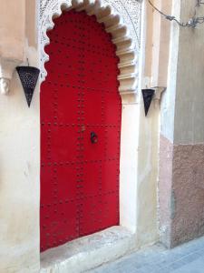 a red door on the side of a building at Riad Yamcha in Meknès