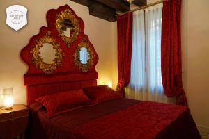 Un dormitorio con una cama roja con un espejo en la pared. en Granda Sweet Suites, en Venecia