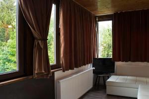 a living room with two windows and a couch at Apartament Mountain Life in Buşteni