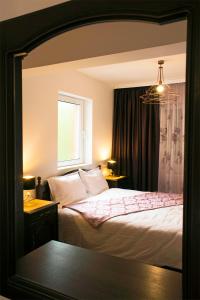 a reflection of a bedroom with a bed and a window at Apartament Mountain Life in Buşteni