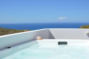 a bathtub in a boat with the ocean in the background at Milos Zen Suites in Adamas
