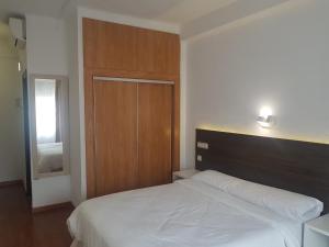 a bedroom with a white bed and a wooden headboard at Hotel Torremolinos Centro in Torremolinos