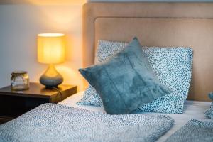 ein blaues Kissen auf dem Bett in der Unterkunft Siesta Sziget - Balaton-parti Apartmanok in Siófok