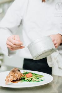 un chef sosteniendo una olla sobre un plato de comida en Hôtel Montmirail, en Gigondas