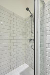 a bathroom with a shower with white tiles at Schieszl Apartments Zamárdi 3 in Zamárdi