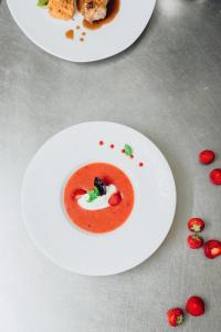 two plates of tomato soup on a table with strawberries at Hôtel Montmirail in Gigondas