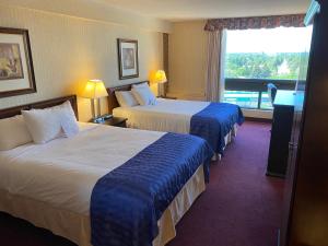 a hotel room with two beds and a window at Ramada by Wyndham Lethbridge in Lethbridge