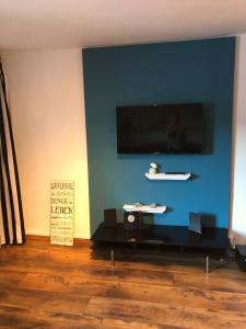 ein Wohnzimmer mit einer blauen Wand und einem Flachbild-TV in der Unterkunft Daddy's home in Hargesheim