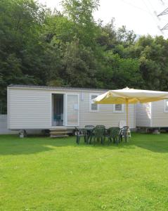 a picnic table and an umbrella in front of a caravan at Camping Alpino - Nature Village in Malcesine