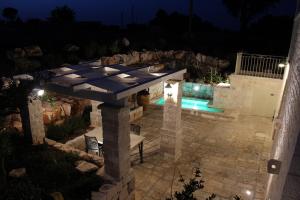 a stone patio with a table and a bench at night at Trulli Arco Antico in Locorotondo