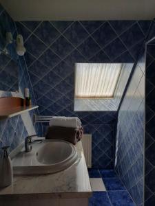 a blue tiled bathroom with a tub and a window at Harmónia Vendégház in Balatonalmádi