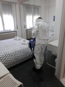 a person in a room with a vacuum cleaner next to two beds at Ciro BED AND BREAKFAST la villetta in Pioltello