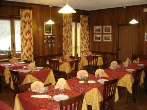 una sala da pranzo con tavoli e sedie rossi e gialli di Hotel Blanchetti a Ceresole Reale