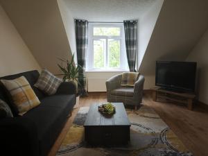 a living room with a couch and a tv at Attic Floor Apartment, City Centre in Inverness