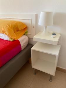 a bed with a white nightstand and a lamp on it at La Isla in Puerto de Mazarrón