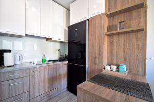 uma cozinha com armários de madeira e um frigorífico preto em Apartamenty NK em Mielno